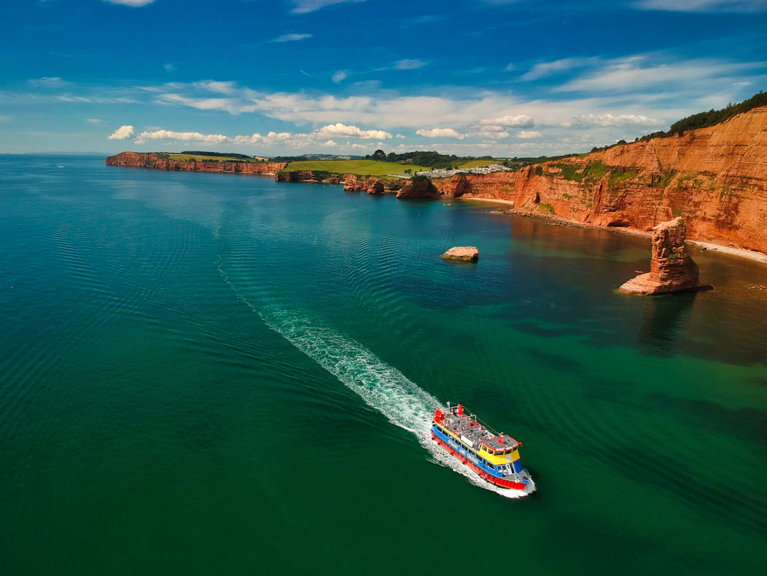 Bateau longeant des falaises rouges au-dessus d'une mer verte